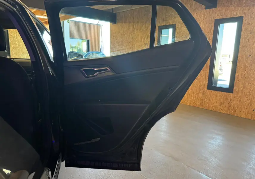 Vue intérieure sur la porte arrière gauche ouverte du Kia Sportage noir 2022, mettant en valeur les finitions intérieures sombres.