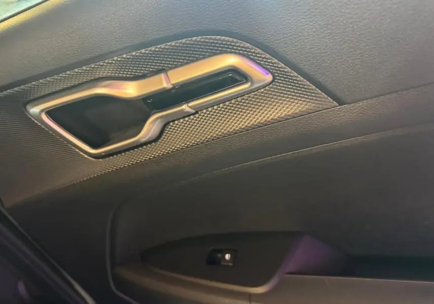 Poignée intérieure arrière droite en métal brossé sur porte noire du Kia Sportage 2022 diesel hybride.