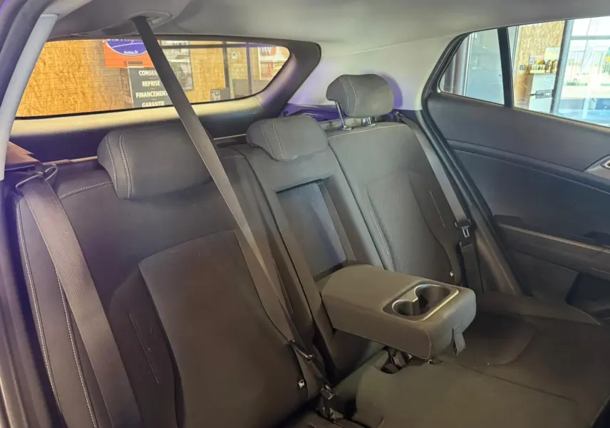 Vue intérieure de la banquette arrière noire du Kia Sportage 2022 avec accoudoir central et ceintures de sécurité visibles.