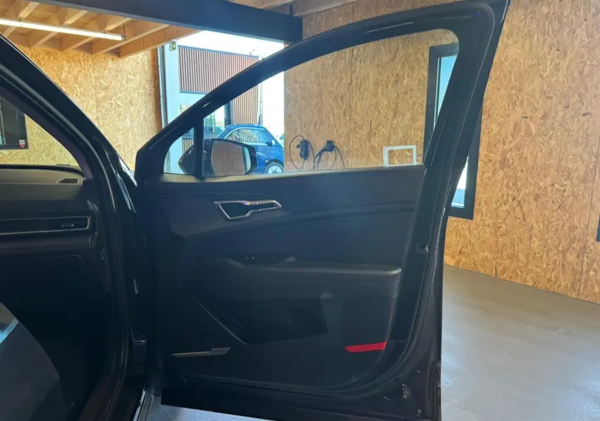 Vue intérieure de la porte avant gauche noire du Kia Sportage 2022, avec garniture sombre et poignée argentée.