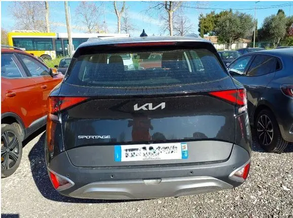 Vue 3/4 avant gauche d’un KIA SPORTAGE noir 2022 avec calandre distinctive et feux allumés en intérieur showroom.