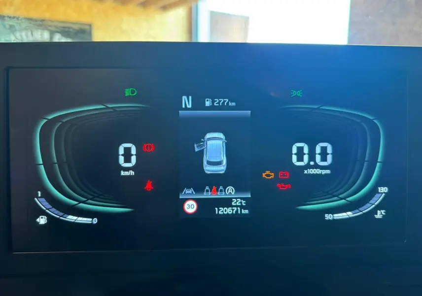 Tableau de bord numérique du Kia Sportage noir 2022, affichant vitesse, régime, autonomie et alertes moteur.