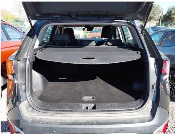 Profil côté gauche d’un KIA Sportage noir 2022 avec jantes alliage et détails chromés sous un plafond en bois.