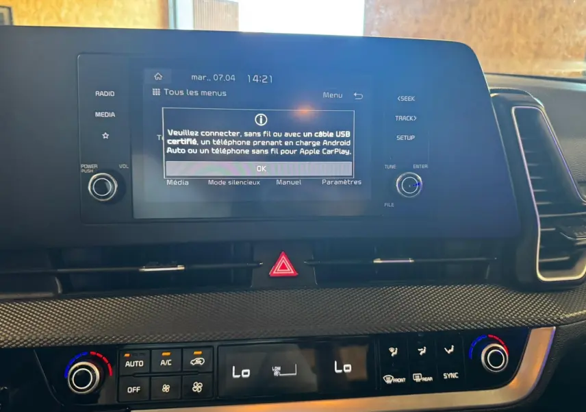 Gros plan sur l’écran central et la console de climatisation du Kia Sportage noir, affichant les réglages multimédia et température.