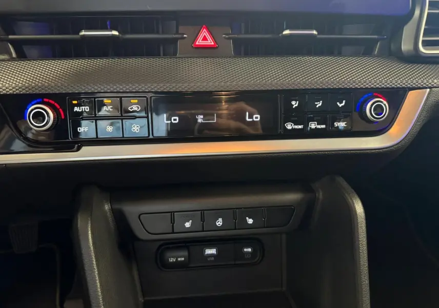 Tableau de bord du Kia Sportage 2022 noir, vue frontale centrée sur la commande de climatisation digitale et les boutons chauffants.