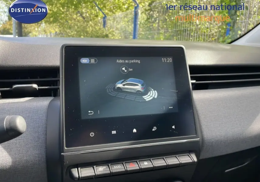 Vue intérieure du tableau de bord de la Renault Clio 2025, écran tactile affichant l'aide au parking, ambiance grise et moderne.