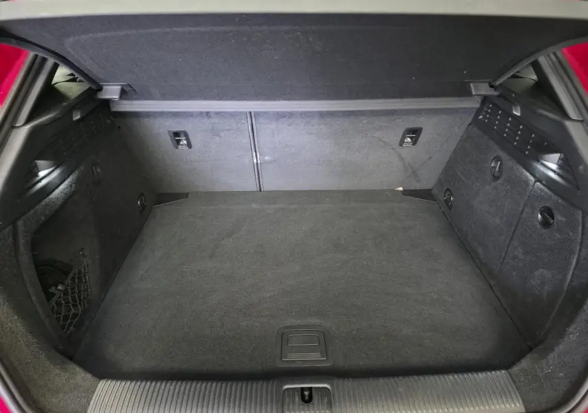 Coffre ouvert de l'Audi A3 Sportback rouge, montrant l'espace de chargement et la moquette noire.