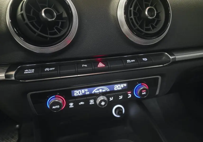Détail du tableau de bord noir de l'Audi A3 Sportback 2019 avec commandes climatisation bi-zone et aérateurs ronds chromés.