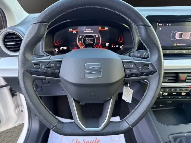 Vue rapprochée du volant cuir multifonctions de la SEAT Ibiza blanche 2023 avec tableau de bord digital et écran tactile.
