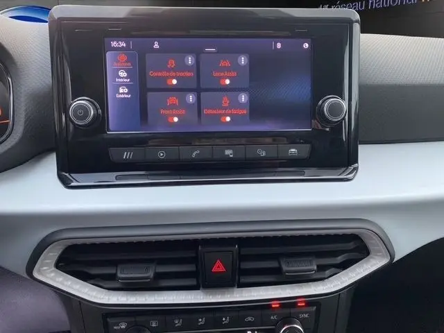 Gros plan sur l’écran tactile central noir du tableau de bord de la SEAT Ibiza blanche, affichant les aides à la conduite.
