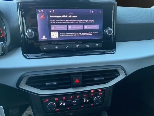 Vue rapprochée du tableau de bord de la SEAT Ibiza blanche 2023, avec écran tactile central et commandes climatisation rétroéclairées.