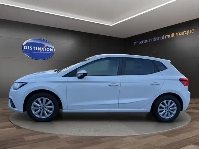 Vue de profil droit d'une SEAT Ibiza blanche 2023 avec vitres arrière surteintées dans un showroom.