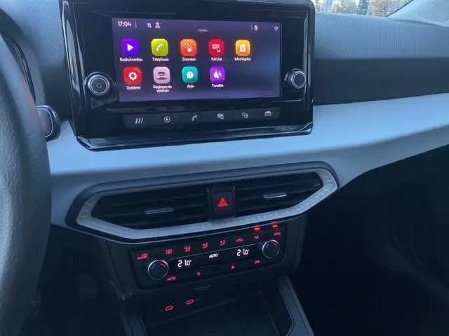 Vue rapprochée du tableau de bord de la SEAT Ibiza blanc 2023, avec écran tactile central et commandes climatisation rouges.