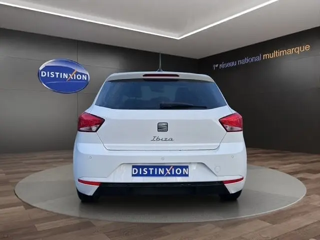 Vue arrière d'une SEAT Ibiza blanche 2023 avec vitres arrière surteintées dans un showroom.