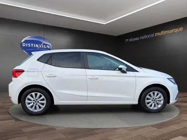Vue de profil côté gauche d'une SEAT Ibiza blanche 2023 avec vitres arrière surteintées dans un showroom.