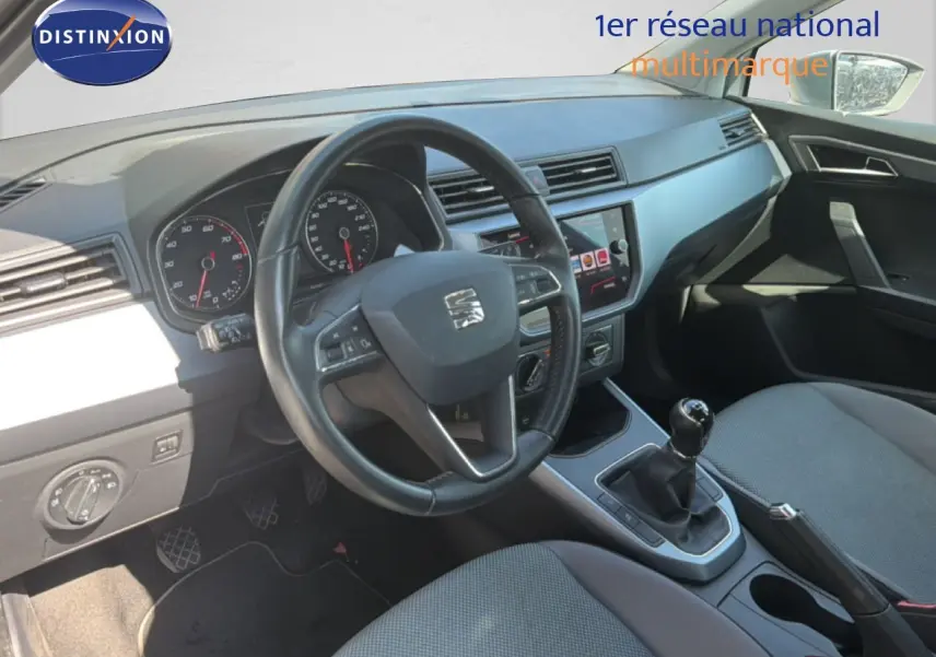 Vue intérieure côté conducteur du tableau de bord et levier de vitesses manuel d'une SEAT Arona 2018 avec sellerie tissu grise.