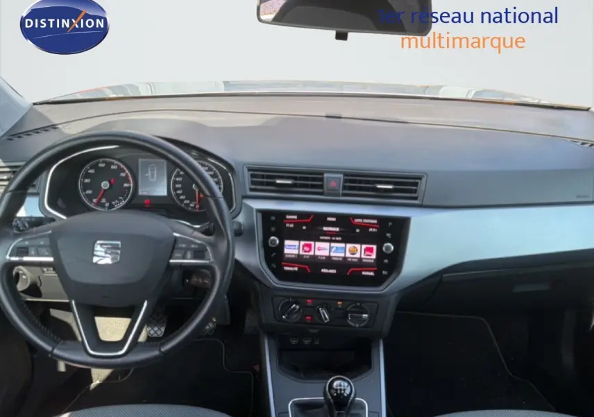 Vue intérieure frontale du tableau de bord et volant noir d'une SEAT Arona 2018 avec écran tactile et commandes manuelles.