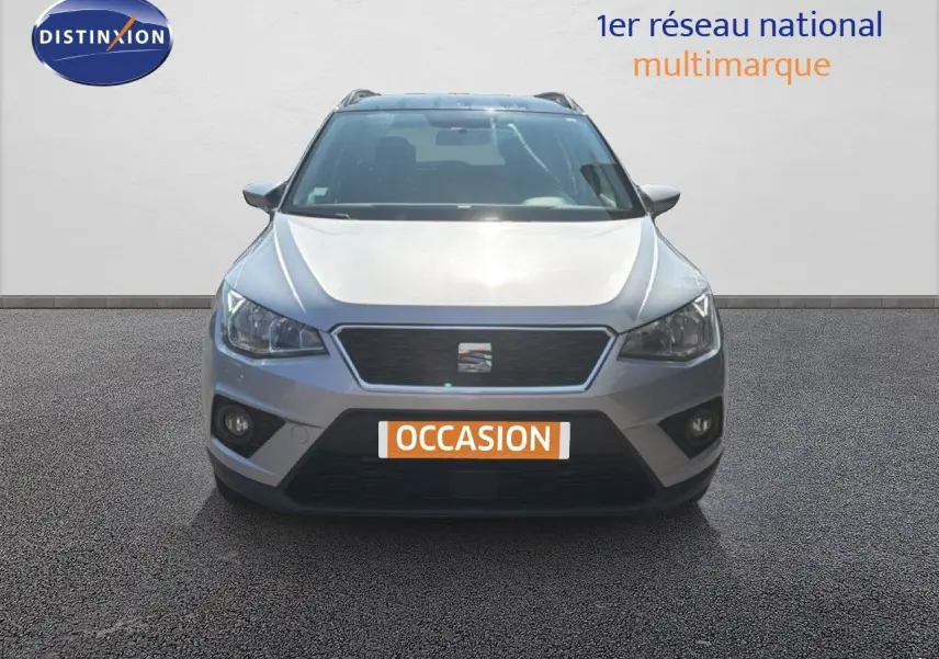 Vue frontale d'une SEAT Arona gris urbain avec calandre noire et plaque "OCCASION" visible sur un sol bitumé.