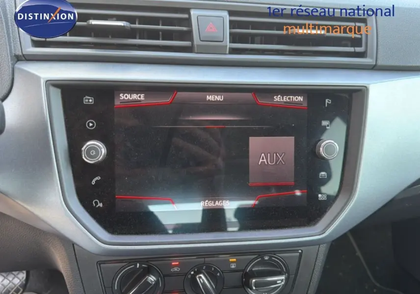 Vue rapprochée de l’écran tactile central du tableau de bord du SEAT Arona gris urbain avec toit noir, affichant le menu AUX.