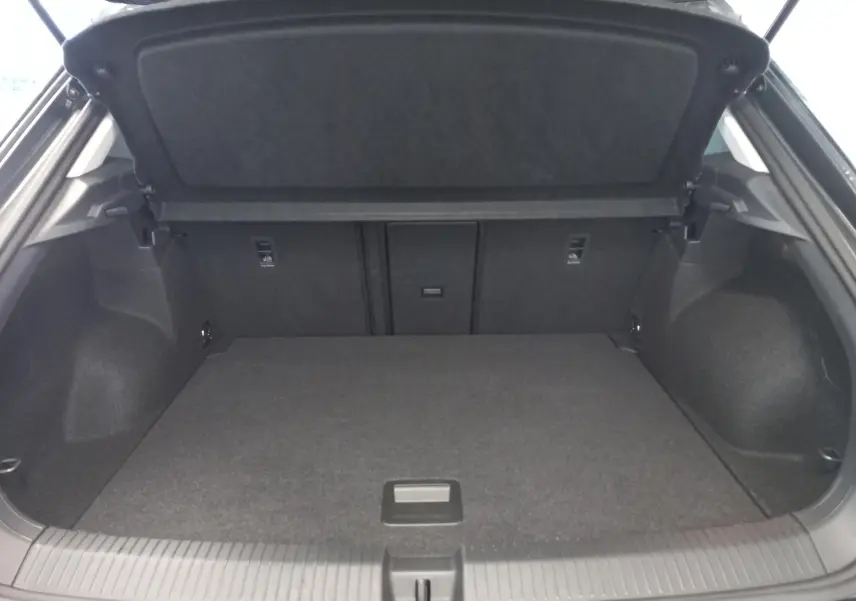 Vue intérieure du coffre ouvert du Volkswagen T-Roc 2025, montrant un espace de chargement propre et bien fini en tissu noir.