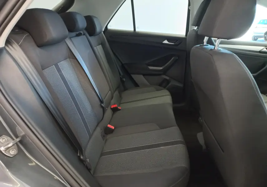 Vue intérieure côté gauche des sièges arrière noirs du Volkswagen T-Roc 2025 Gris Indium avec ceinture de sécurité visible.