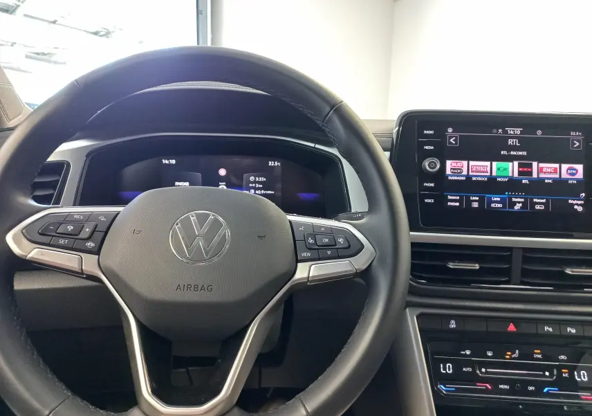 Vue intérieure centrée sur le volant Volkswagen T-Roc avec tableau de bord numérique et écran multimédia tactile.