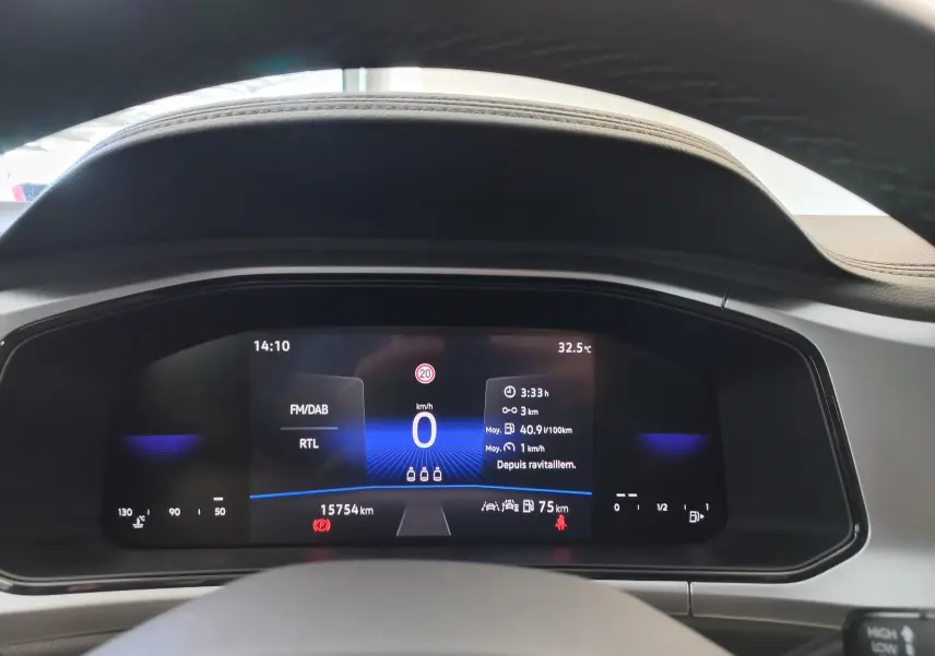 Tableau de bord numérique du Volkswagen T-Roc 2025 affichant la vitesse, la radio et la température extérieure à 32,5°C.