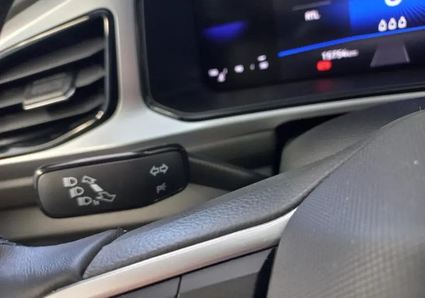 Gros plan sur la commande des clignotants à gauche du volant dans l’habitacle du Volkswagen T-Roc gris Indium.