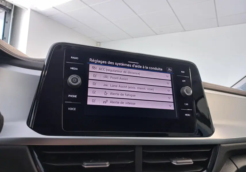 Écran tactile central du Volkswagen T-Roc 2025 affichant les réglages des aides à la conduite dans un intérieur clair.