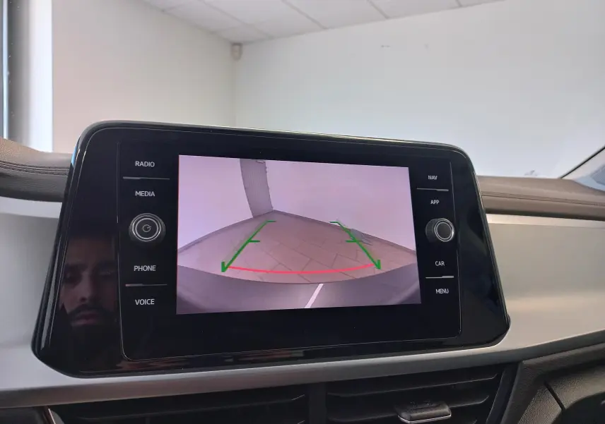Écran central du Volkswagen T-Roc 2025 montrant la caméra de recul avec guidage vert et rouge, intérieur beige.