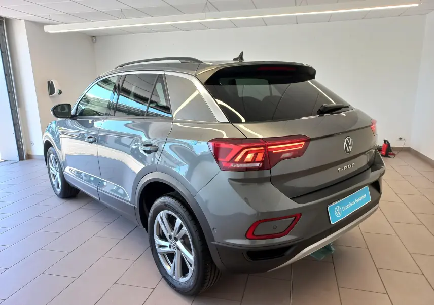 Vue 3/4 arrière droite du Volkswagen T-Roc gris Indium avec jantes alliage 17 pouces Valencia en intérieur showroom.