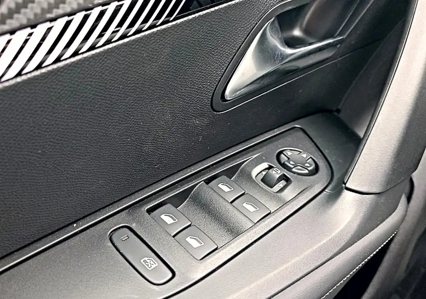 Gros plan sur les commandes de vitres électriques et rétroviseurs sur la porte côté conducteur d'une Peugeot 2008.