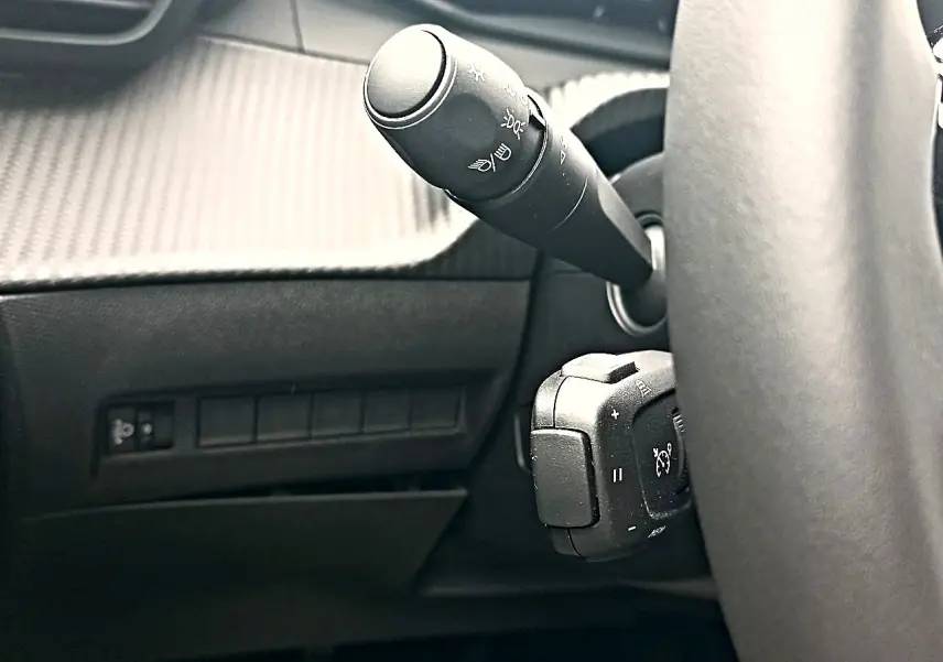 Gros plan sur la commande des phares et régulateur de vitesse derrière le volant d’un Peugeot 2008 1.2 100 allure.