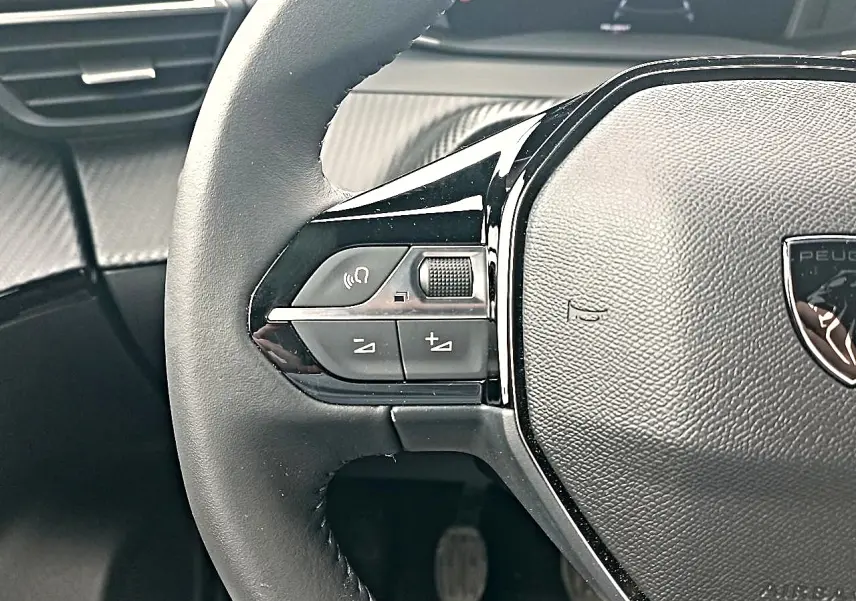 Gros plan sur le volant multifonction noir de la Peugeot 2008 1.2 100 allure avec commandes audio intégrées.