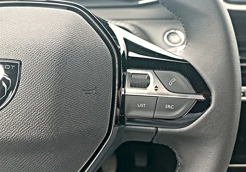 Gros plan sur le volant noir du Peugeot 2008 1.2 100 allure avec commandes multifonctions côté droit.