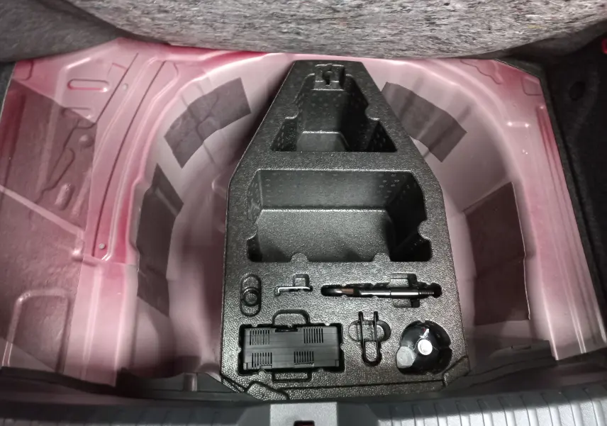 Coffre ouvert d’une SEAT Ibiza 2025 Rouge Désir, vue plongeante sur le rangement sous plancher avec outils intégrés.