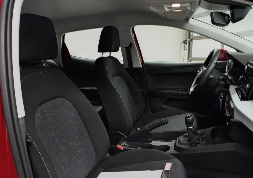 Vue intérieure côté conducteur de la SEAT Ibiza 2025 Rouge Désir, montrant les sièges noirs et la boîte manuelle.