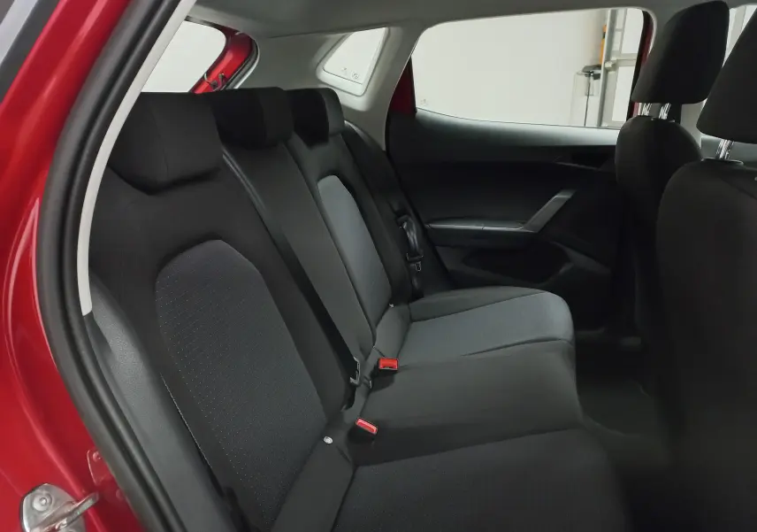 Vue intérieure côté arrière droit de la SEAT IBIZA 2025 rouge désir, montrant les sièges arrière en tissu noir et gris.