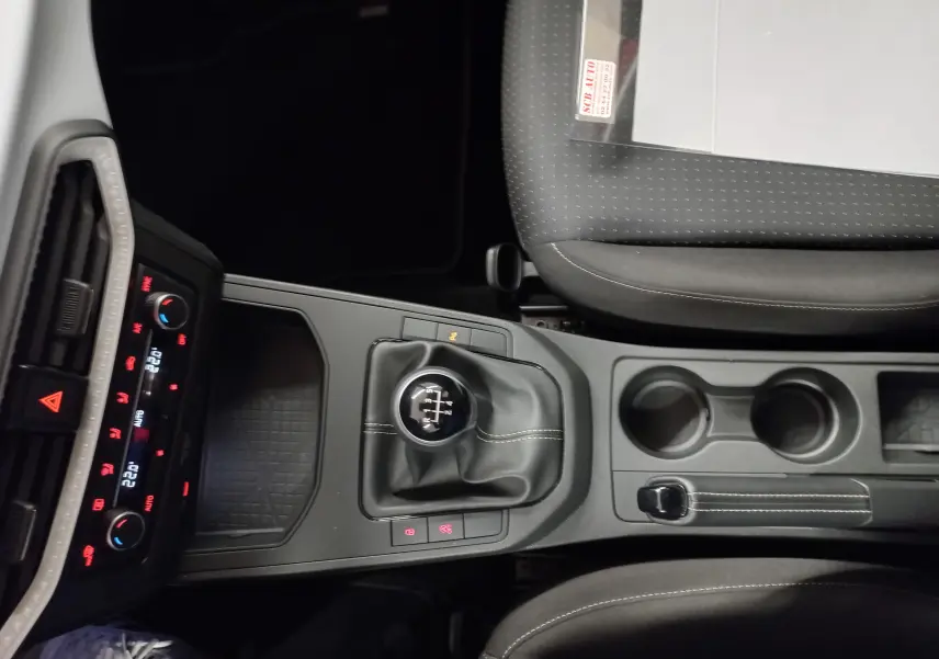 Vue plongeante sur la console centrale de la SEAT IBIZA 2025 rouge désir, avec levier de vitesse manuel et commandes climatisation.