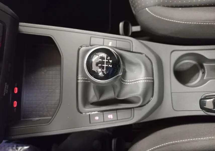Vue plongeante sur le levier de vitesses manuel de la SEAT IBIZA 2025, avec coutures blanches sur soufflet noir.
