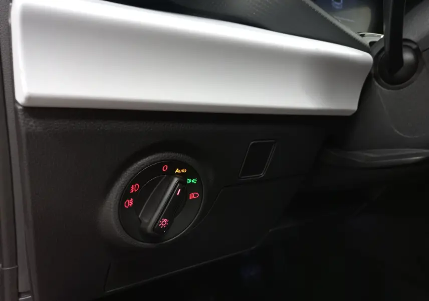 Gros plan sur le bouton de commande des phares dans l’habitacle noir et blanc d’une SEAT Ibiza Rouge Désir 2025.