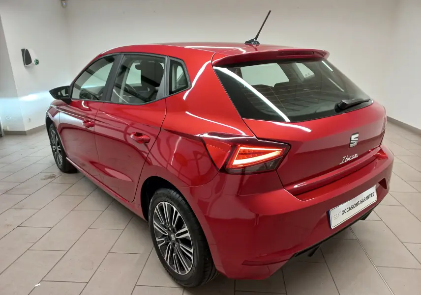 SEAT Ibiza 2025 Rouge Désir vue 3/4 arrière droit, feux LED allumés et jantes alliage distinctives.