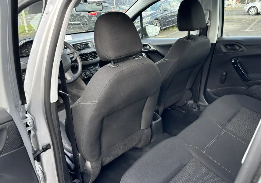 Intérieur arrière de la Peugeot 208 gris argent 2017, vue côté gauche avec sièges tissu noir et tableau de bord visible.