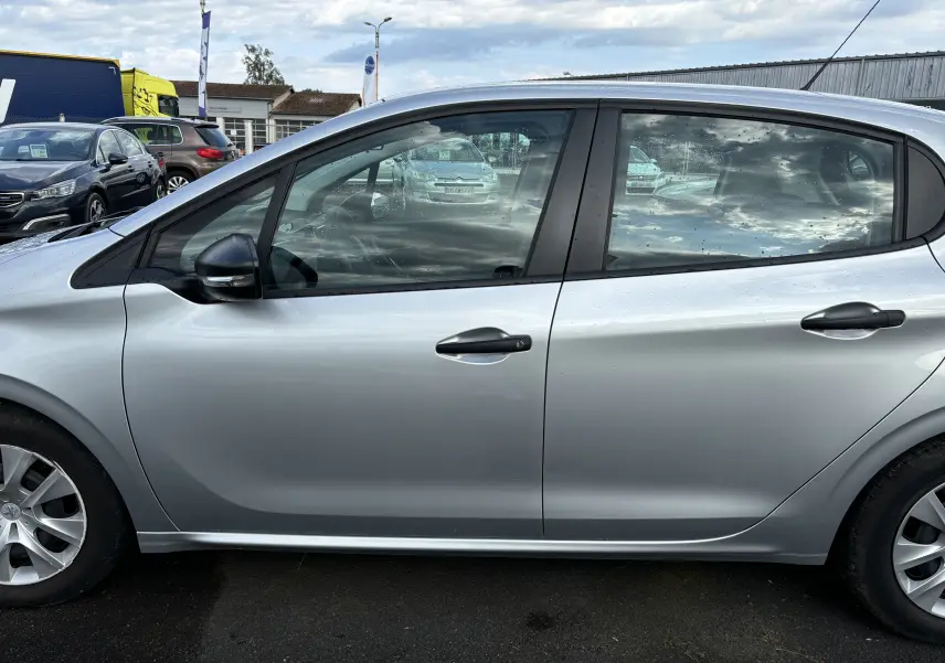 Profil côté gauche d'une Peugeot 208 gris argent 5 portes de 2017 avec rétroviseur noir et jantes alliage simple.