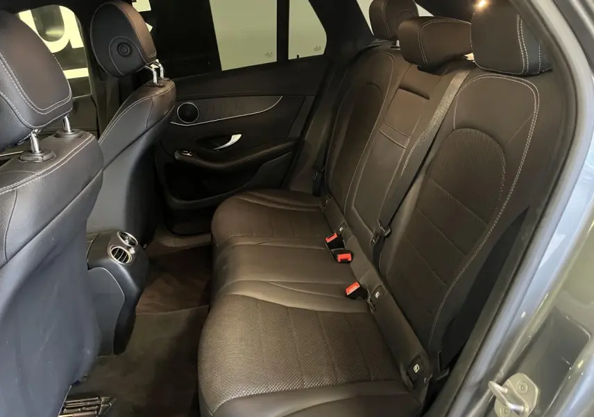 Vue intérieure côté droit montrant la banquette arrière en similicuir noir avec surpiqûres blanches du Mercedes GLC gris.