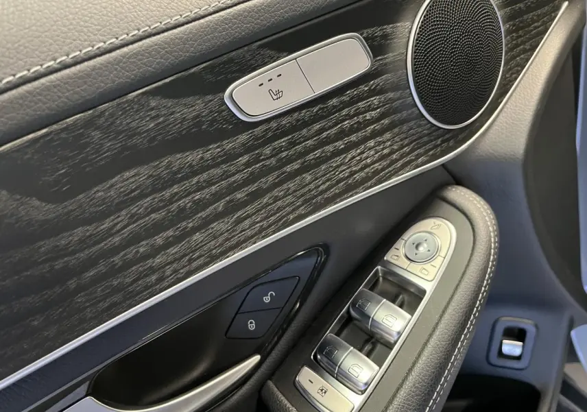 Détail de la porte avant gauche du Mercedes GLC gris, avec commandes des vitres et bouton de siège chauffant.