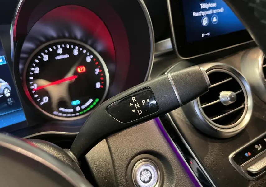 Gros plan sur la commande de boîte automatique et le tableau de bord du Mercedes GLC gris, avec affichage digital et ventilation ronde.