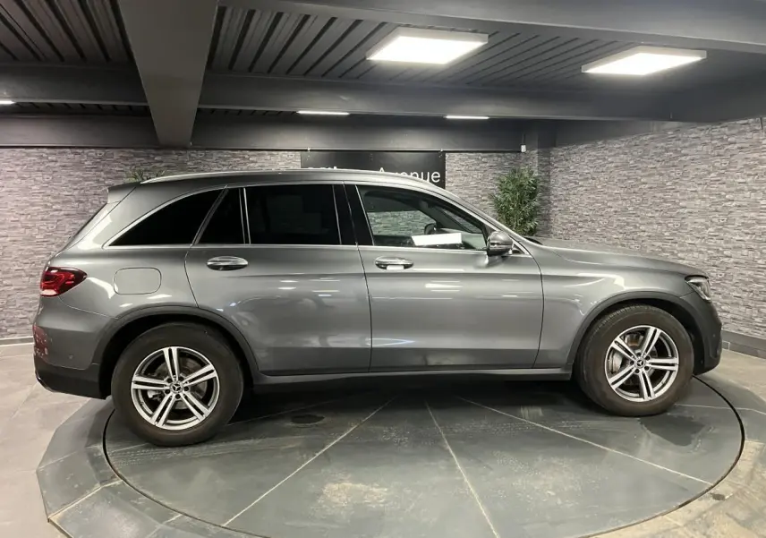 Profil côté gauche d'un Mercedes GLC gris métallisé 2019 en intérieur avec jantes alliage 5 branches.
