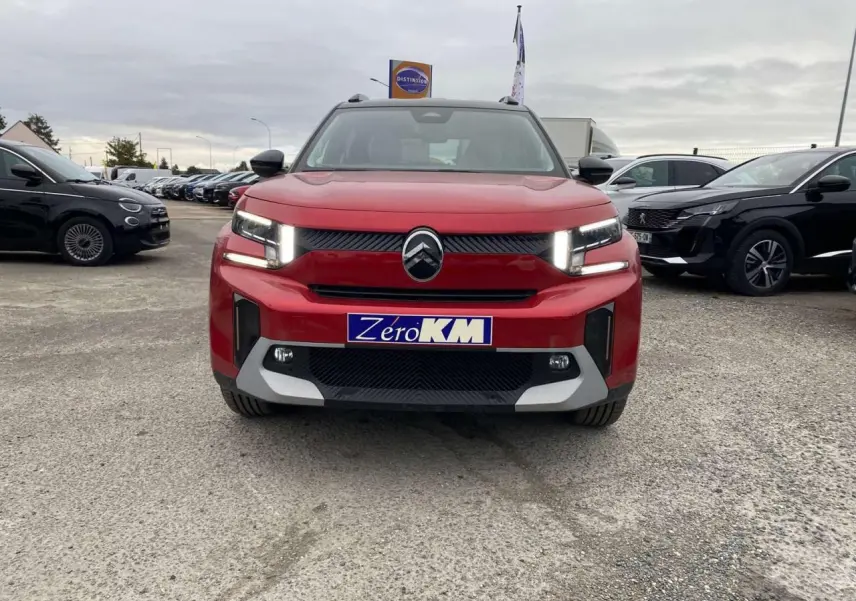 Vue frontale d'un Citroën C3 Aircross 2025 rouge Elixir avec toit noir et feux LED allumés sur parking.
