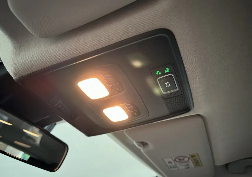 Plafonnier intérieur allumé avec bouton SOS et partie du pare-soleil dans une Renault Clio gris clair 2025.